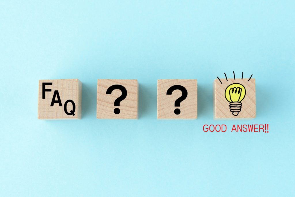 FAQとクエスチョンマーク、電球のイラストが描かれた木製ブロック